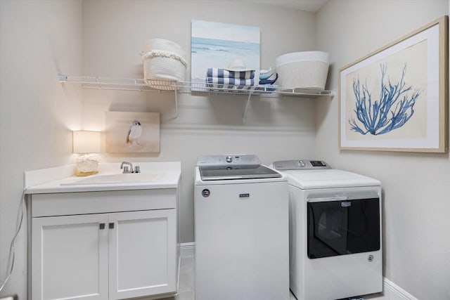 clothes washing area featuring washing machine and clothes dryer, baseboards, a sink, and cabinet space