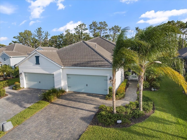 view of front facade featuring an attached garage, a front lawn, stucco siding, decorative driveway, and a tiled roof