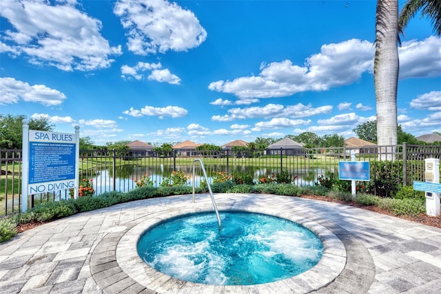 view of pool featuring a water view, a community hot tub, fence, and a residential view