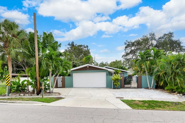 view of front of house featuring a gate, an attached garage, driveway, and stucco siding
