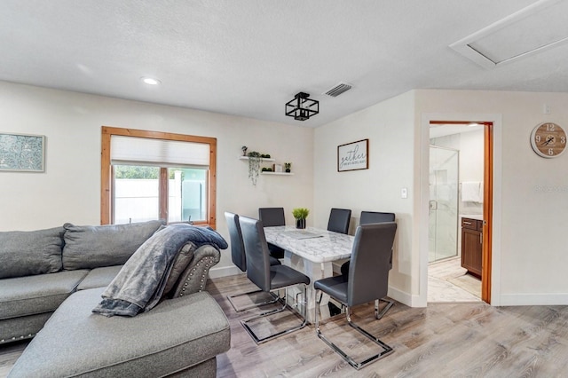 living room with visible vents, baseboards, light wood-type flooring, recessed lighting, and a textured ceiling