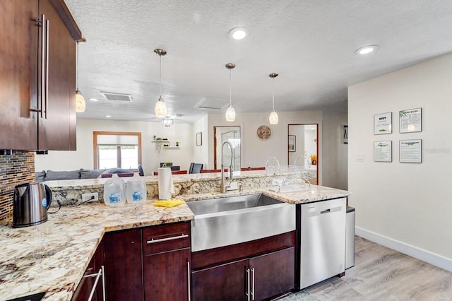 kitchen with a sink, dishwasher, light wood-type flooring, visible vents, and pendant lighting