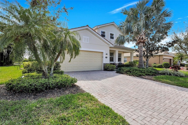 view of front of property featuring an attached garage, decorative driveway, and stucco siding