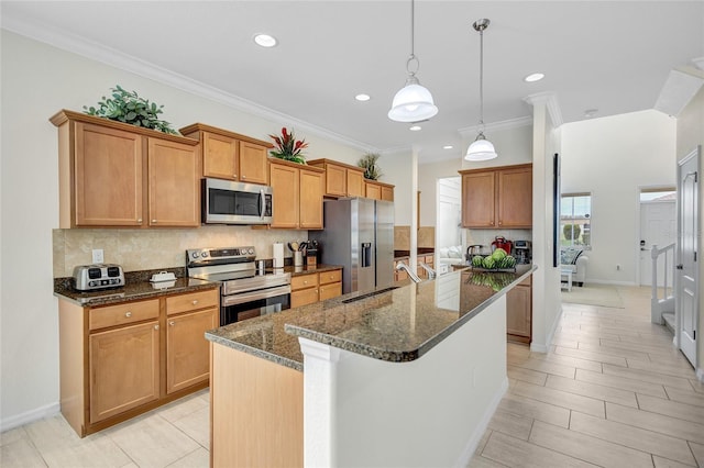 kitchen with an island with sink, dark stone counters, tasteful backsplash, a sink, and appliances with stainless steel finishes