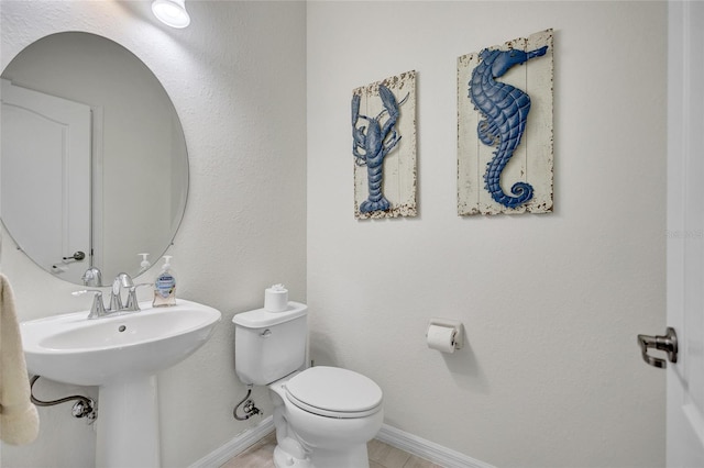 bathroom with toilet, baseboards, and a sink