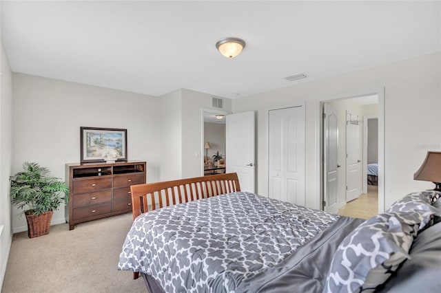 bedroom with baseboards, visible vents, light carpet, and a closet