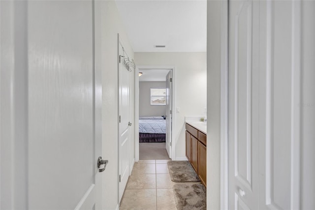 ensuite bathroom featuring connected bathroom, vanity, tile patterned floors, baseboards, and visible vents