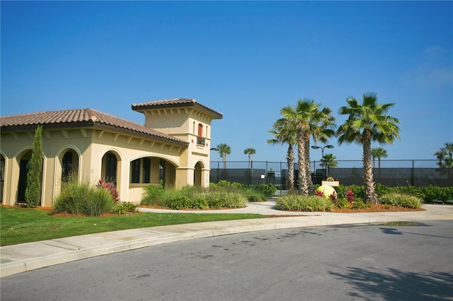 view of property exterior with fence, a tile roof, and stucco siding