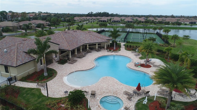 pool featuring fence, a water view, a patio area, and a residential view