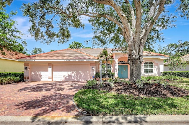 4730 Old Farm Rd, Sarasota, FL 34233 - mediterranean / spanish-style house featuring an attached garage, stucco siding, decorative driveway, and a tile roof
