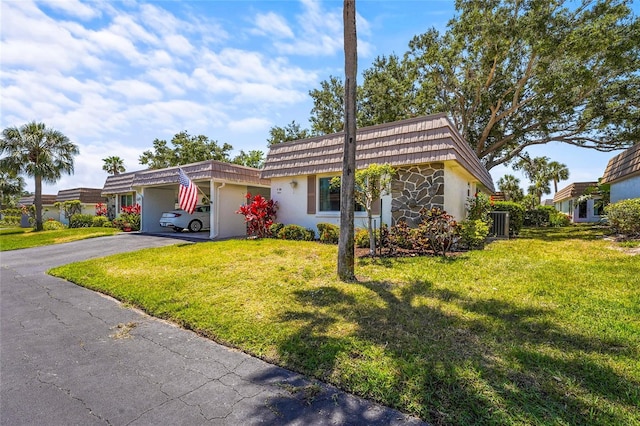 view of front of home with an attached carport, mansard roof, a front lawn, and aphalt driveway