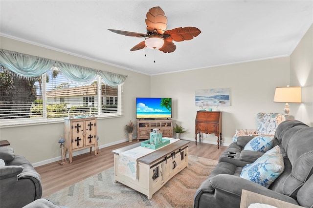living area with ceiling fan, ornamental molding, baseboards, and light wood-style flooring