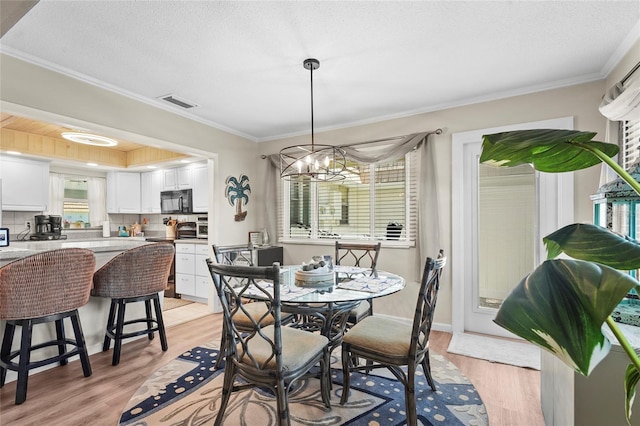 dining room with visible vents, ornamental molding, a healthy amount of sunlight, and light wood finished floors