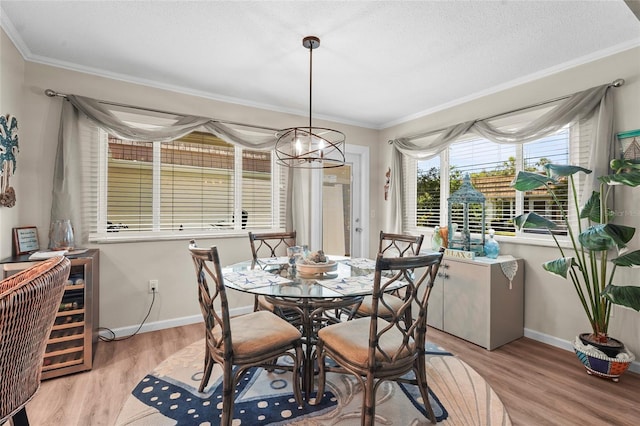 dining area featuring crown molding, baseboards, a notable chandelier, and light wood finished floors