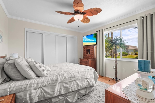 bedroom with a closet, a ceiling fan, light wood-style floors, and crown molding