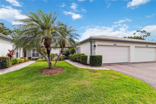 view of front of house featuring a garage, aphalt driveway, a front yard, stucco siding, and a tile roof