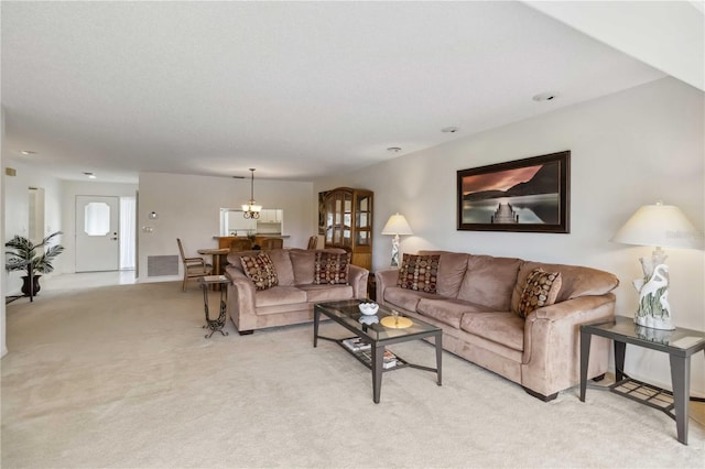 living room featuring visible vents, a chandelier, and light carpet
