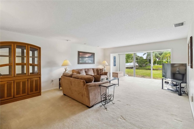 living area featuring carpet floors, a textured ceiling, and visible vents