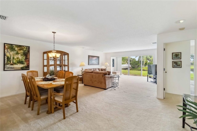 dining space with a notable chandelier, light carpet, and visible vents