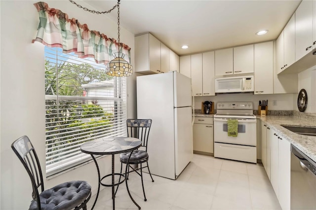 kitchen with light tile patterned flooring, light stone countertops, white appliances, recessed lighting, and decorative light fixtures