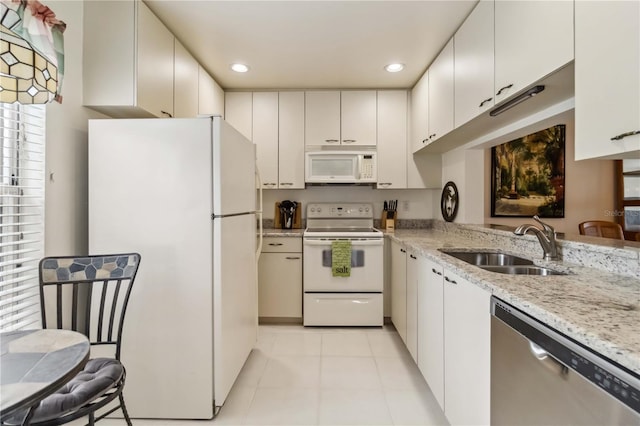 kitchen featuring white appliances, light stone countertops, recessed lighting, white cabinetry, and a sink