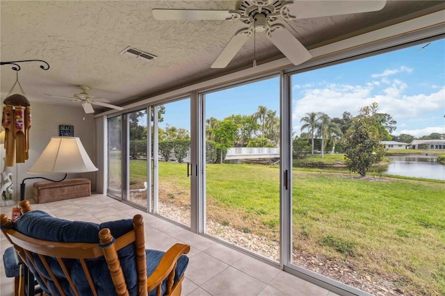 sunroom with a ceiling fan, tile patterned flooring, a water view, and visible vents