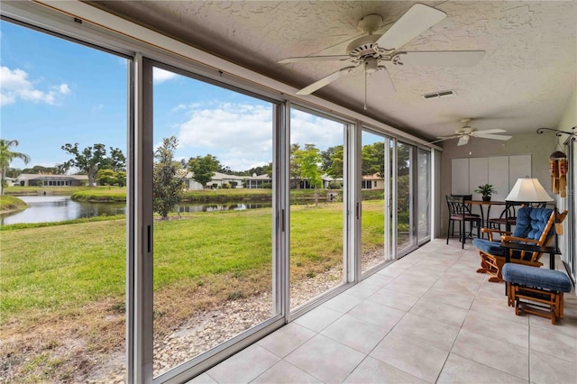 sunroom / solarium featuring ceiling fan, a water view, and a healthy amount of sunlight
