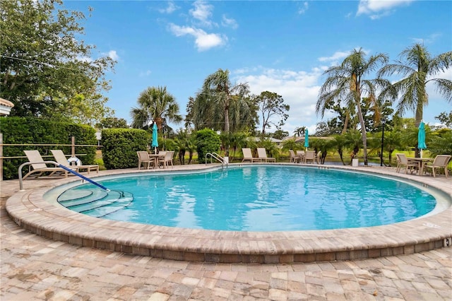 community pool with outdoor dining area and a patio area