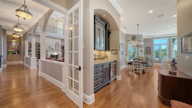 975 Whitakers Ln, Sarasota, FL 34236 - bar area with ornamental molding, wine cooler, light wood-style flooring, baseboards, and backsplash