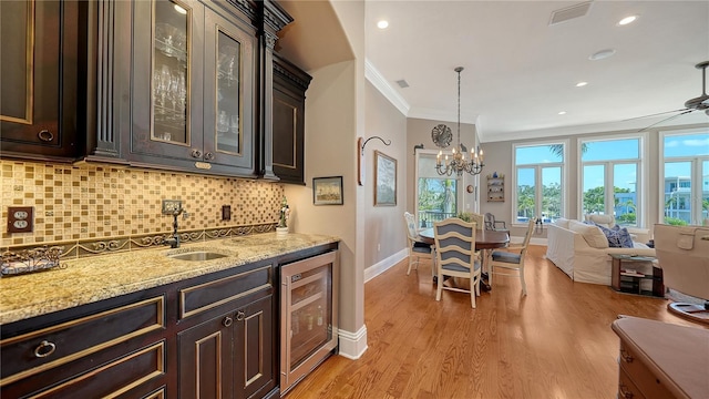 975 Whitakers Ln, Sarasota, FL 34236 - kitchen featuring wine cooler, crown molding, baseboards, tasteful backsplash, and light wood-style floors