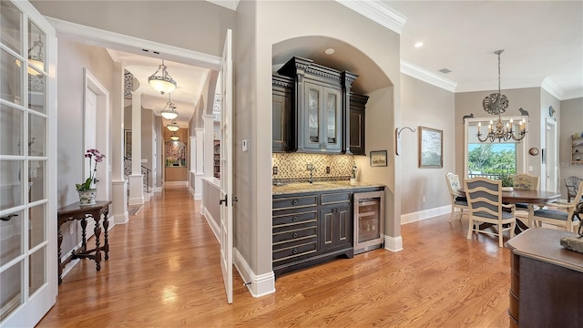 975 Whitakers Ln, Sarasota, FL 34236 - bar area with beverage cooler, ornamental molding, decorative backsplash, light wood-style flooring, and a chandelier