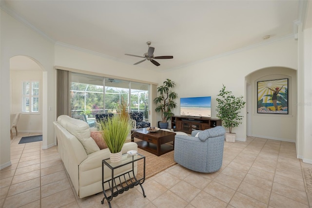 living area featuring crown molding, ceiling fan, arched walkways, baseboards, and light tile patterned floors