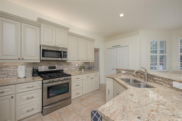kitchen with a sink, decorative backsplash, stainless steel appliances, and cream cabinets