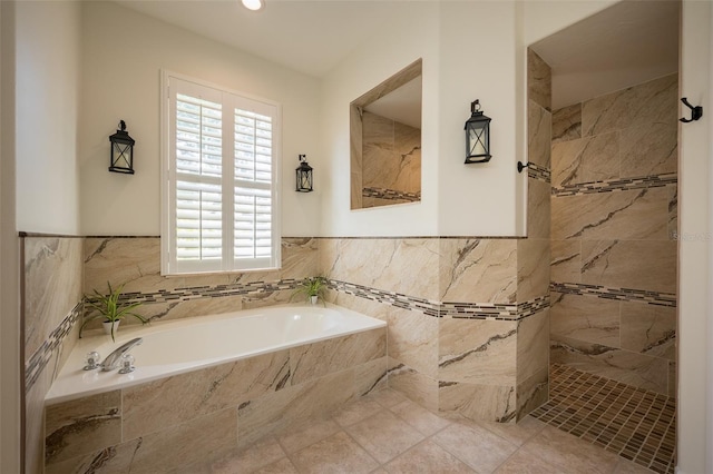 full bath featuring plenty of natural light, a bath, a tile shower, and a wainscoted wall