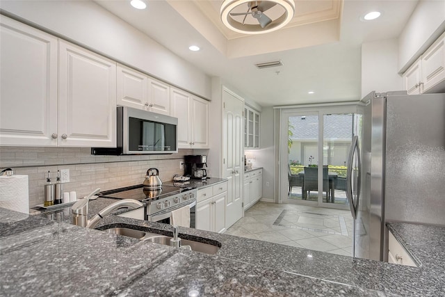 kitchen featuring appliances with stainless steel finishes, dark stone countertops, recessed lighting, white cabinetry, and tasteful backsplash