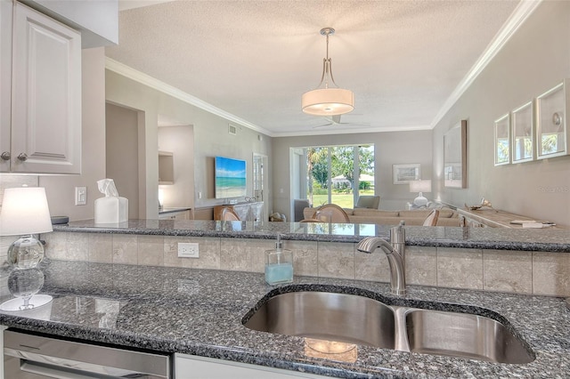 kitchen featuring crown molding, stainless steel dishwasher, a sink, open floor plan, and dark stone counters