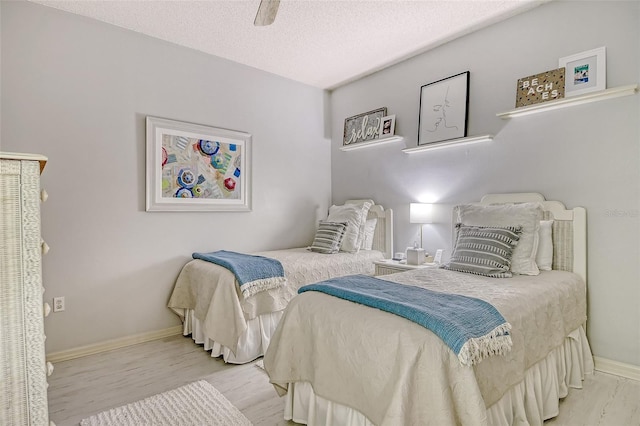 bedroom with baseboards, a textured ceiling, ceiling fan, and wood finished floors