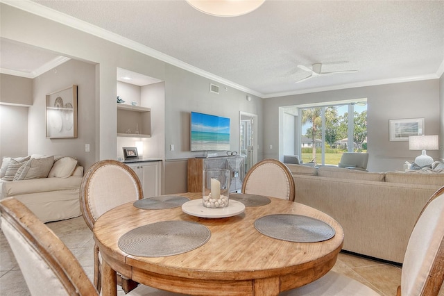 dining space featuring crown molding, light tile patterned flooring, a textured ceiling, and visible vents