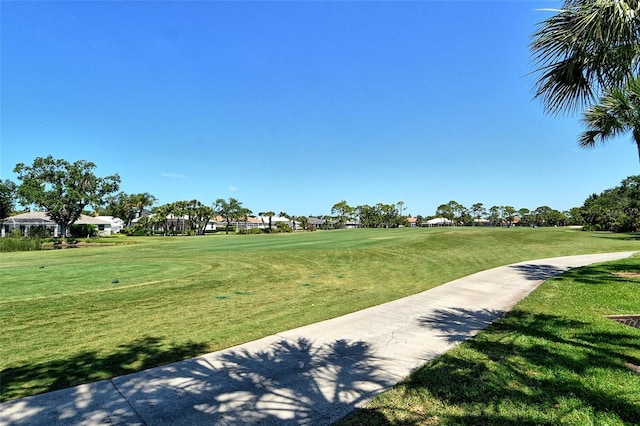 view of property's community with a residential view, a yard, and golf course view
