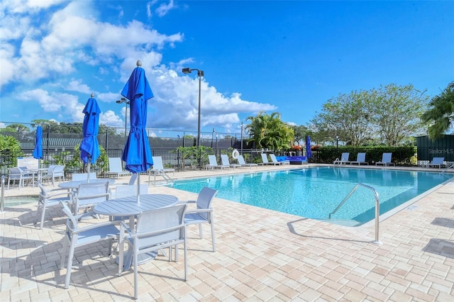 community pool with a patio and fence