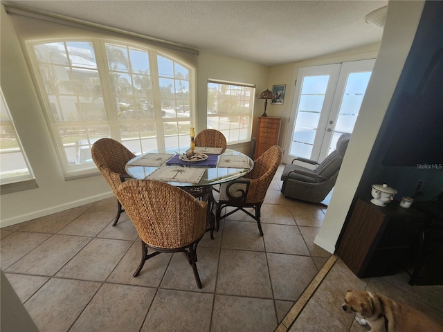 tiled dining area with french doors, a textured ceiling, and baseboards