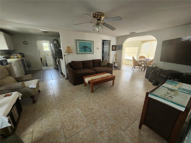 living room with arched walkways, light tile patterned flooring, and a ceiling fan