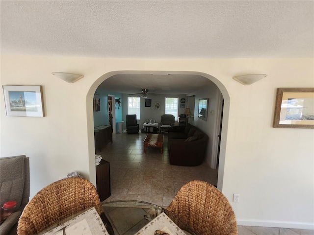 hall featuring arched walkways and a textured ceiling