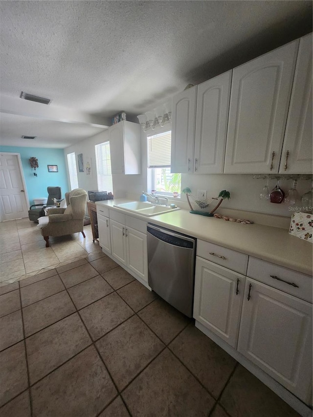 kitchen with dishwasher, a sink, white cabinets, a textured ceiling, and light tile patterned flooring