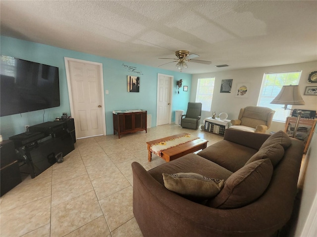 living area with light tile patterned floors, ceiling fan, and a textured ceiling
