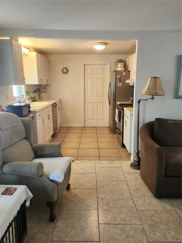 kitchen featuring appliances with stainless steel finishes, light countertops, white cabinetry, a sink, and open floor plan