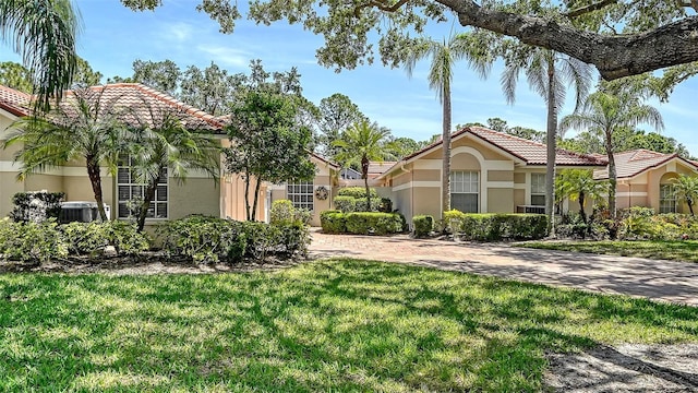 3984 Lyndhurst Ct, Sarasota, FL 34235 - view of front facade featuring cooling unit, a front lawn, a tile roof, and stucco siding