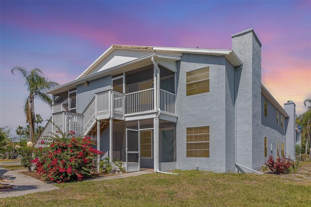 3781 59th Ave W Unit 3781, Bradenton, FL 34210 - back of house at dusk with stucco siding, a sunroom, stairs, a lawn, and a chimney