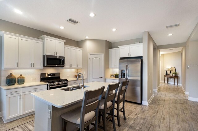 4815 Deep Creek Ter, Parrish, FL 34219 - kitchen featuring appliances with stainless steel finishes, a sink, a kitchen island with sink, white cabinetry, and light countertops