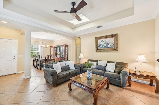 living area featuring arched walkways, a tray ceiling, ceiling fan, light tile patterned flooring, and crown molding